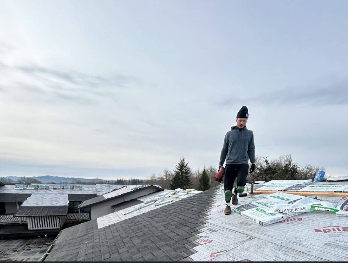 Drake Wilson installing underlayment on an apartment roof replacement in Coeur d'Alene